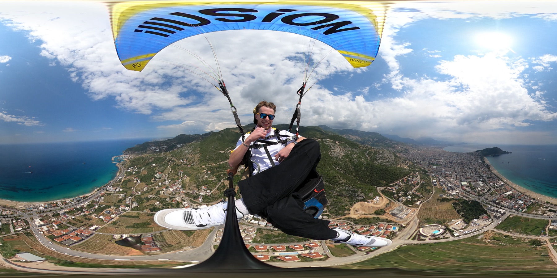 Grafter Media team member paragliding over the coast, giving a thumbs up